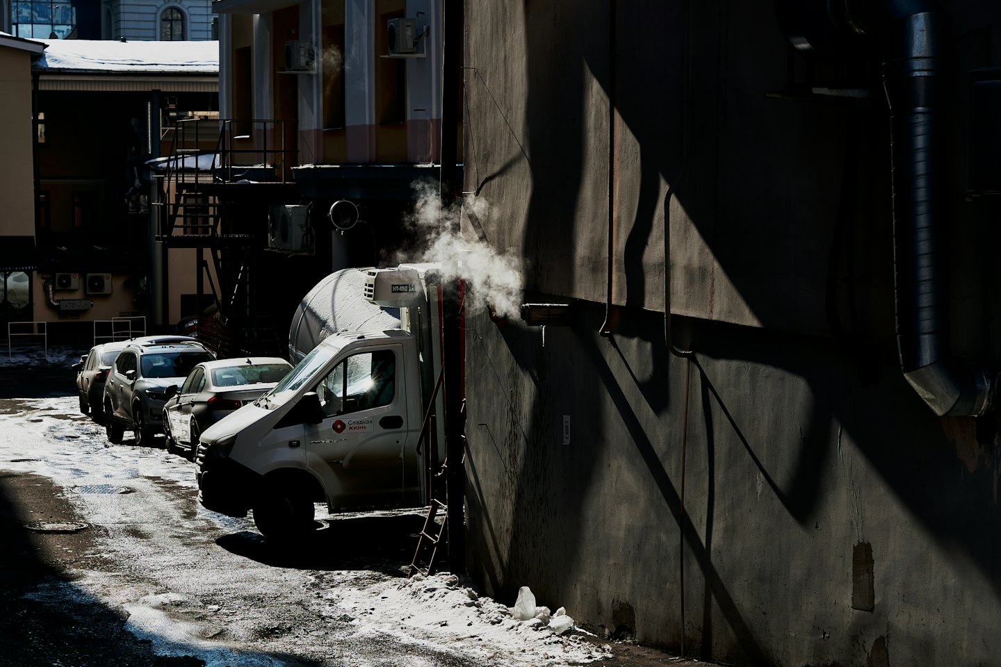 Furgone per consegne refrigerato parcheggiato in una strada cittadina innevata.